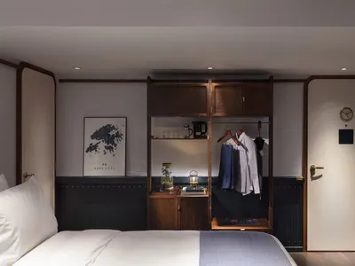 現代臥室，展示一張鋪有白色床品的床、一個放有衣物的木質衣櫃，以及裝飾物件。
