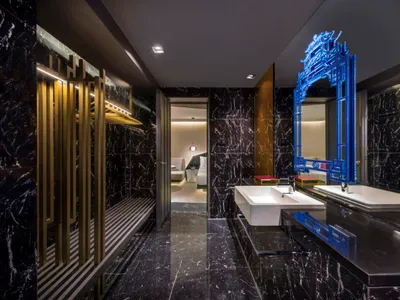 A modern bathroom with black marble walls and a glass partition.