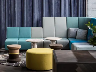Modern restaurant with a textured concrete wall, concrete tables, and a blue chair.
