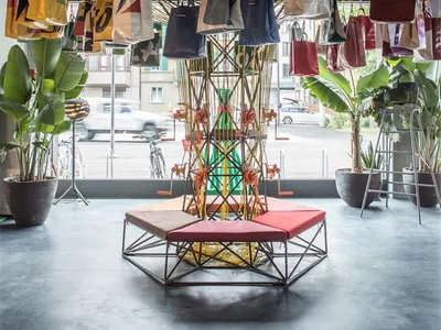 Industrial-style retail storefront with hanging fabric bags, metal structures, and glass elements.