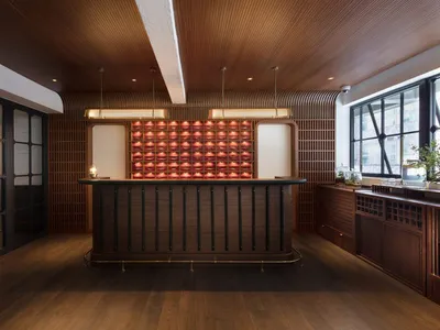 An industrial-style restaurant bar with a wooden counter, red lighting, and wooden walls