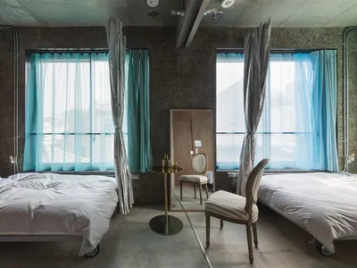 Minimalist bedroom with concrete walls and two twin beds.