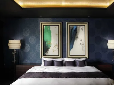 A modern bedroom featuring a bed with fabric and wooden headboard, surrounded by black circular-patterned wallpaper, and flan