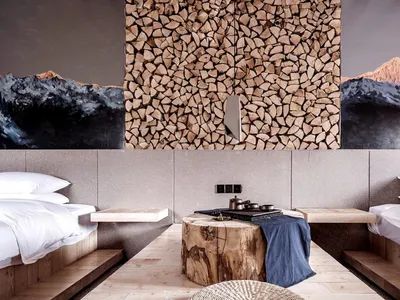 A modern bedroom featuring a log coffee table with a blue blanket, two twin beds with white bedding, and a wall stacked with