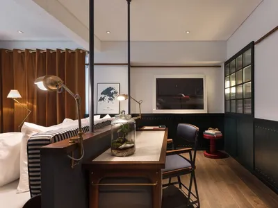 Modern home office space with a desk, chair, desk lamp, and framed picture, featuring wood and metal materials.