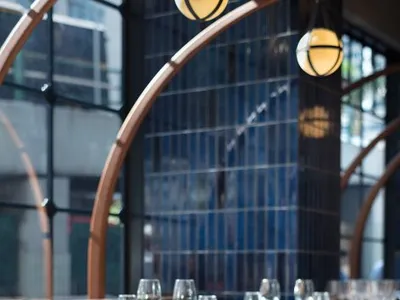 A modern restaurant interior with wooden chairs and tables, glassware, and minimalist decor.