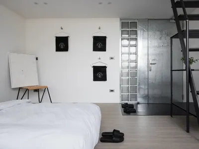 Modern minimalist bedroom with metallic glass door and black metal shelving.