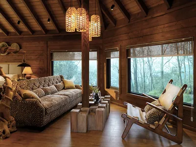 A cozy living room with a wooden ceiling, log walls, and a comfortable sofa with a zebra print cover, surrounded by large win
