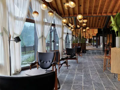 Industrial-style restaurant interior with stone flooring and leather upholstery on chairs.