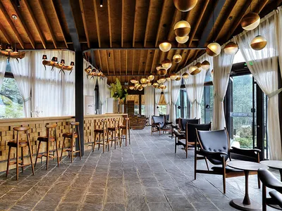 A modern restaurant bar with a wooden pine interior featuring a cozy seating area, high stools, and a polished concrete floor