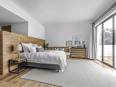 簡約臥室內有木質板材床架、白色的床具，以及木地板上鋪著的灰色地毯。