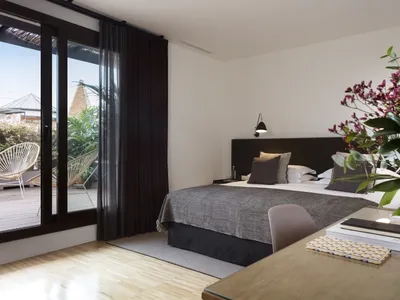 Modern bedroom with a bed, curtain, plants, and a desk.