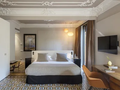 A modern hotel room featuring a king-sized bed, white and gray color scheme, and a large window.