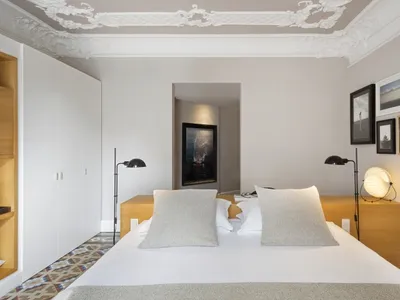 A minimalist bedroom with a large bed, white walls, and wooden headboard and nightstands.