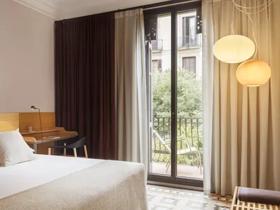 A modern bedroom with a clean, minimalist design featuring neutral-toned fabrics and furniture.