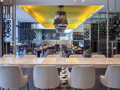 A modern restaurant interior with black and white patterned floor, contemporary lighting fixtures, and a mix of metal, glass,