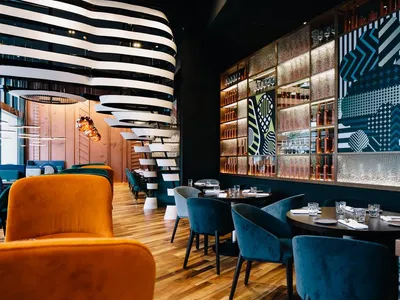 Interior of a modern restaurant featuring metal accents, glass display cases, and wooden furniture.