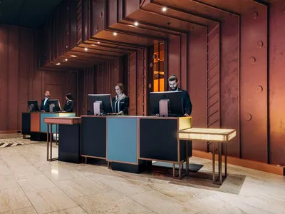 A modern industrial hotel lobby features polished metal and wooden surfaces.