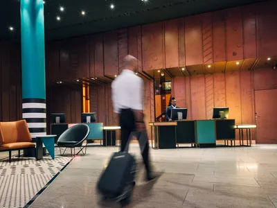 Modern hotel lobby with metallic wood paneling, minimal furniture, and warm lighting.