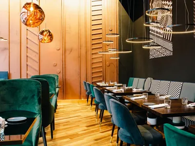Modern restaurant interior with velvet seating and wood accents, featuring contemporary lighting fixtures and a stylish patte