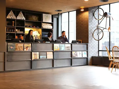 Industrial hotel lobby featuring a metal reception desk with a mixed media design element.