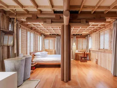 Minimalist bedroom with wooden furniture, white bedding, and large windows
