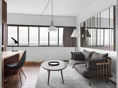 A minimalist living room with a grey sofa, wooden coffee table, and a large window.