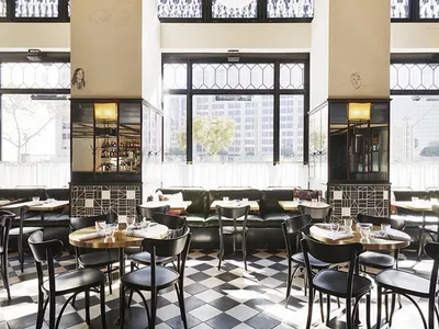A cafe interior with tables and chairs arranged on a checkerboard-patterned floor.