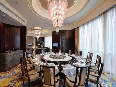 A luxurious dining room with marble tables, glass chandeliers, and wooden chairs.