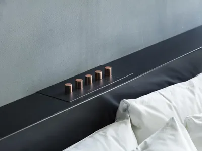 Modern minimalist bedroom featuring a black metal headboard with metallic knobs and white bedding.