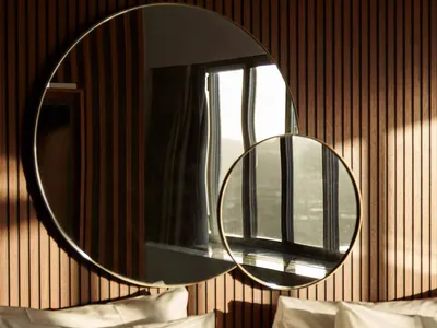 A minimalist bedroom with two circular mirrors mounted on a wooden wall, creating a modern and sleek atmosphere.