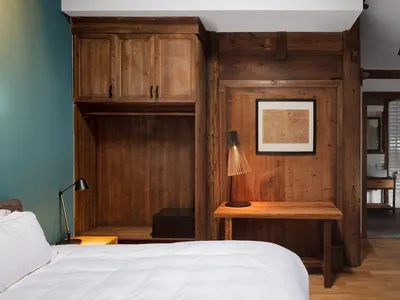 A minimalist bedroom with wooden furniture and decor, including a bed, desk, and a yellow chair.