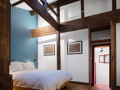 A minimalist bedroom with wooden furniture and white bedding.