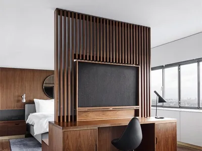 A minimalist bedroom featuring wooden furniture and a large window with a city view.