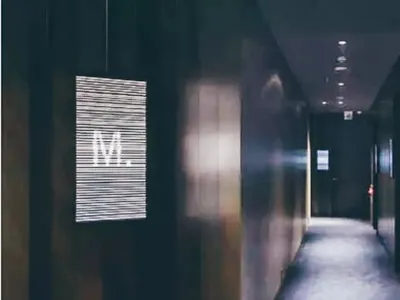 A minimalist corridor interior with metallic signage displaying letters and symbols.
