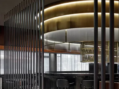 A modern restaurant bar with elegant marble flooring, glass partitions, and metallic accents.