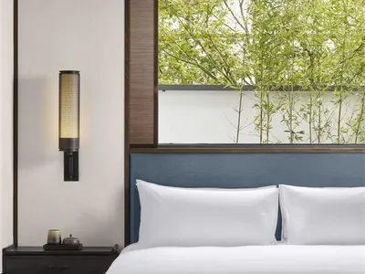 Modern minimalist bedroom featuring fabric walls, a white bed, and clean lines