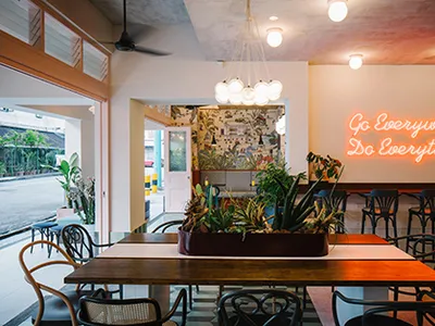 Modern cafe interior featuring sea glass mosaic tile accents, wooden tables, and potted plants.