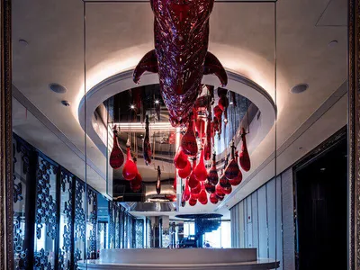 Large, red bull head hanging sculpture in the center of a sleek, modern restaurant interior.