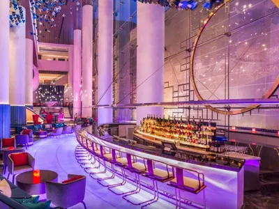 High-end nightclub interior with modern materials, featuring a bar and seating area with illuminated columns and a circular d