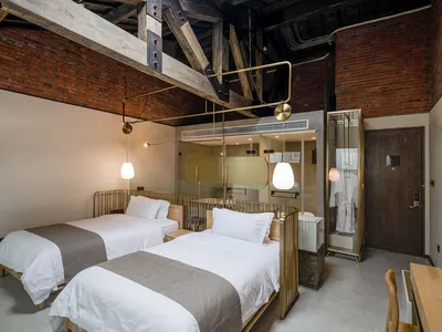 An industrial-style hotel room featuring brick walls and metallic furnishings.