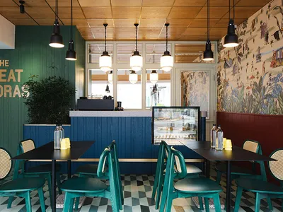 A modern coffee shop with wooden walls, blue tables, and green chairs.