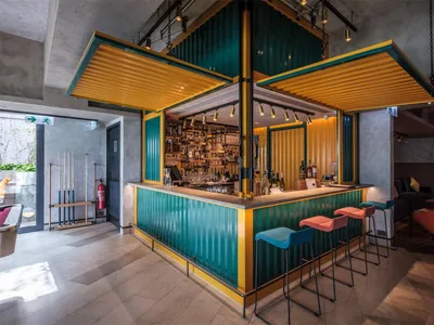 An industrial-style restaurant bar with metal clad modules featuring colorful seating and a well-stocked bar.