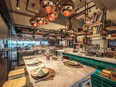 A modern restaurant interior featuring metallic decor and green tiles