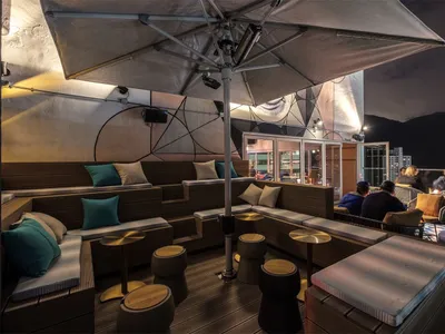 Industrial-style rooftop lounge with wooden seating and fabric cushions.