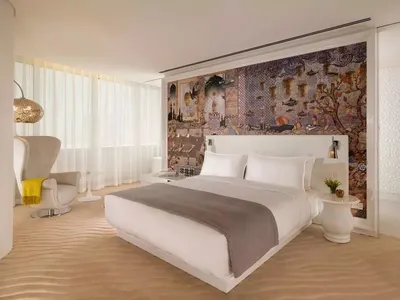 一間現代臥室，配有白色床鋪與裝飾性牆面圖紋。