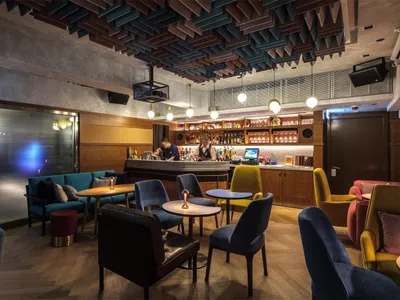 A modern restaurant and bar interior featuring concrete, wood, fabric, metal, and glass materials.