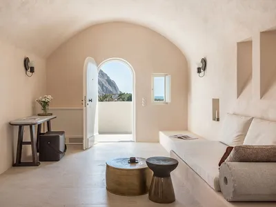 A minimalist living room with concrete flooring, a leather sofa, and a small table.
