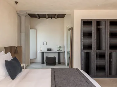 A modern bedroom featuring concrete walls and wooden furniture.