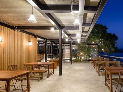 現代工業風餐廳，木製餐桌搭配混凝土地板，鋼樑天花板。